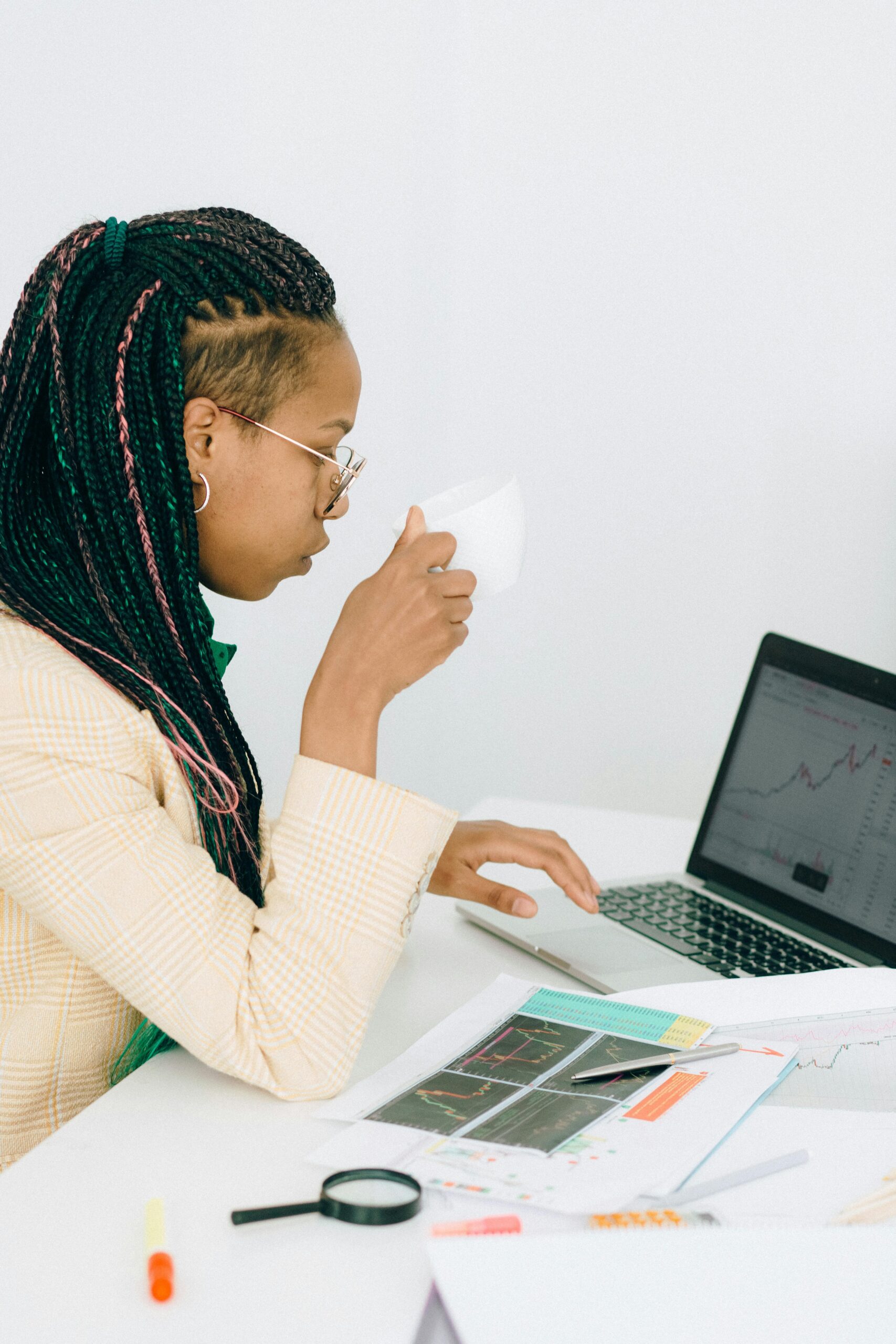 A woman analyzing stock market charts on a laptop while sipping coffee – Financial trading & investment research.